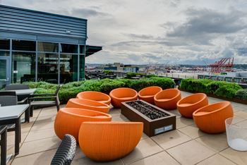A modern outdoor seating area with orange chairs and a table.